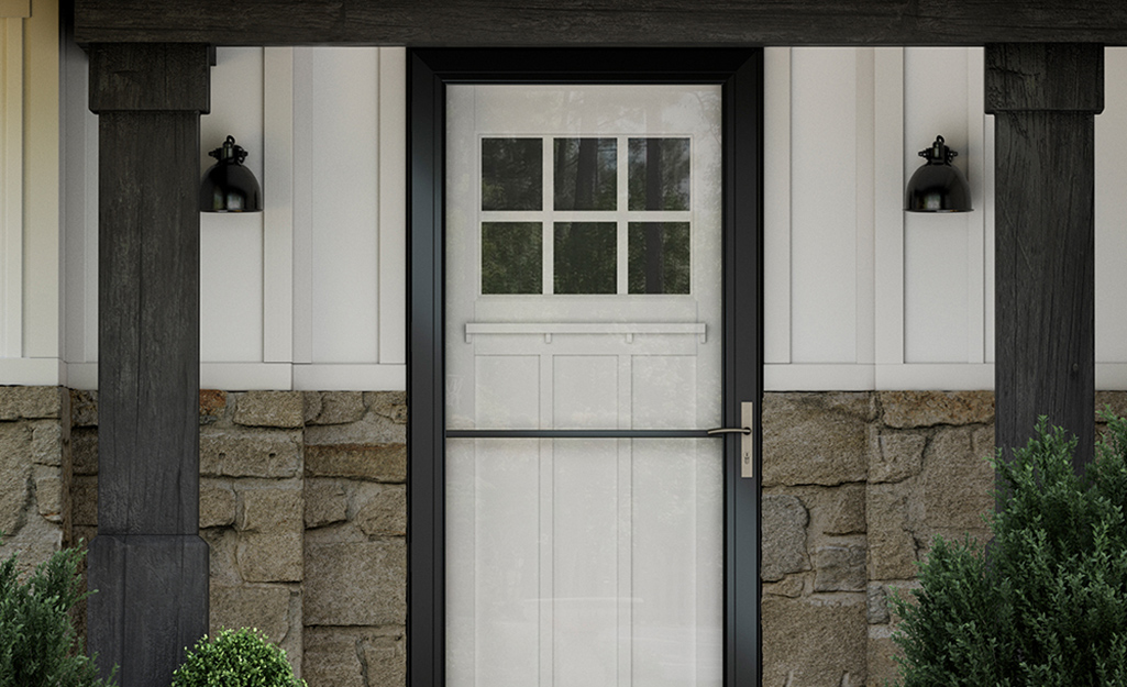 A storm door with a dark frame covers a white front door.