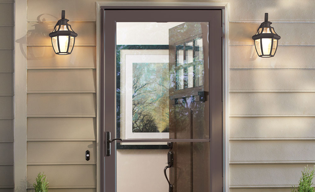 A storm door with a bronze finish covers a doorway with an open front door.