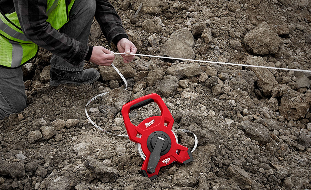 An open reel tape measure on being used on a job site.