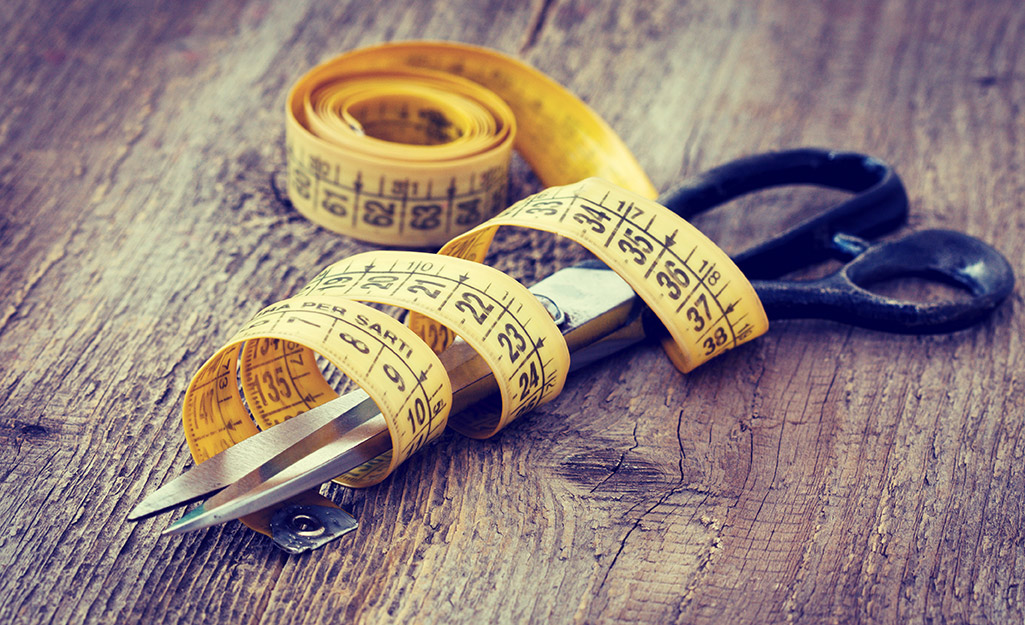 A yellow sewing tape measure on wrapped around a pair of scissors.