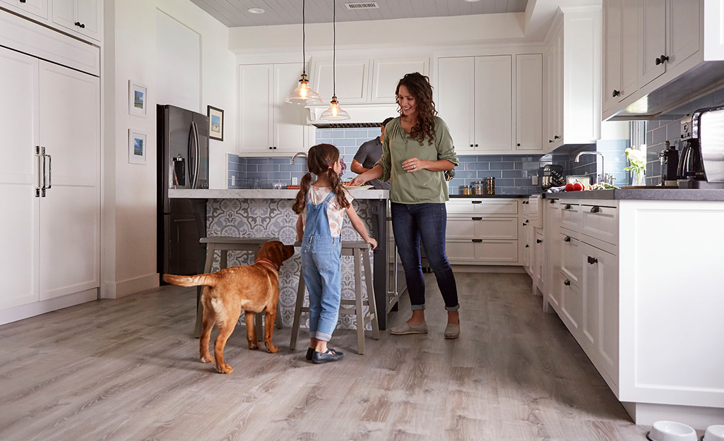 Mom talking to kid and family dog in a kitchen with a tiled floor.