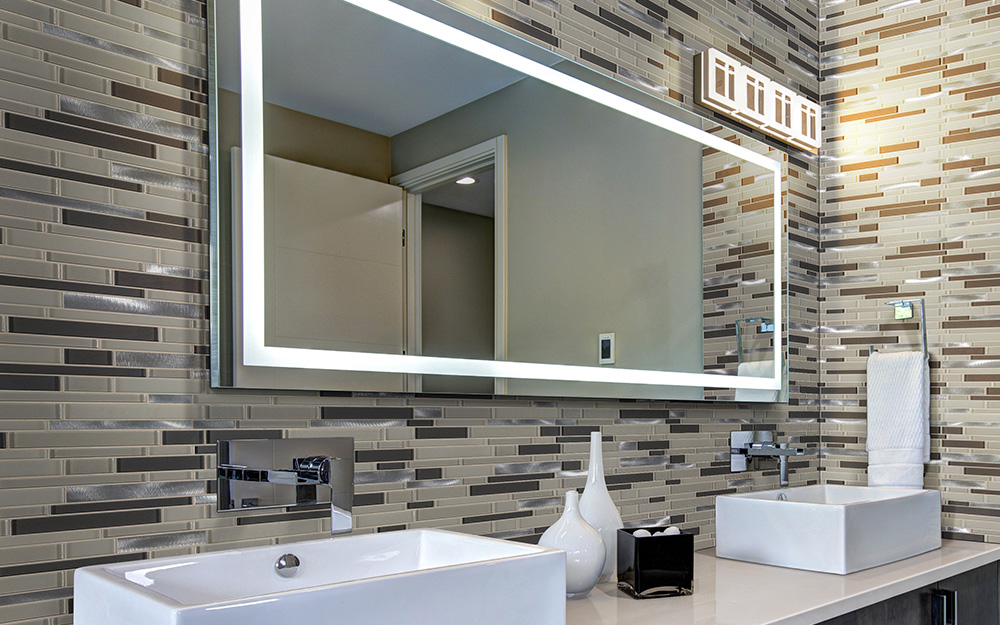 A bathroom with a mosaic tile wall behind the sink. 