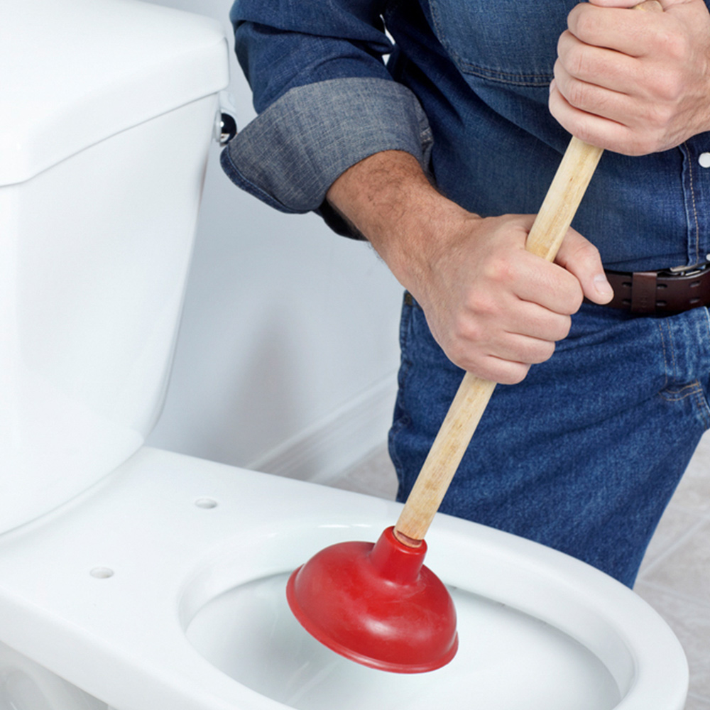 Someone using a plunger to clear a toilet clog.