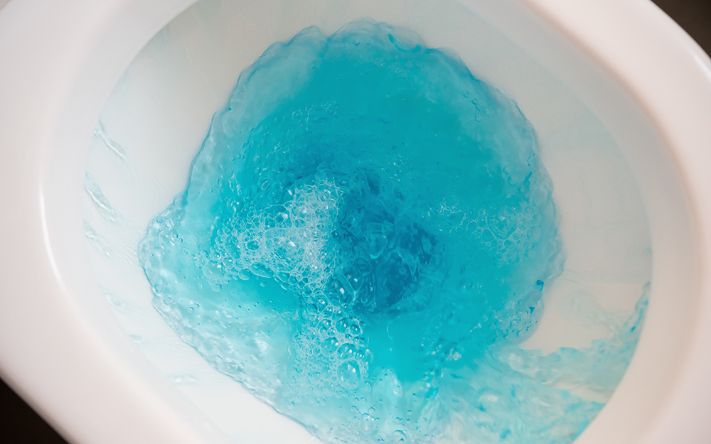 Blue water flushing in a white toilet bowl.