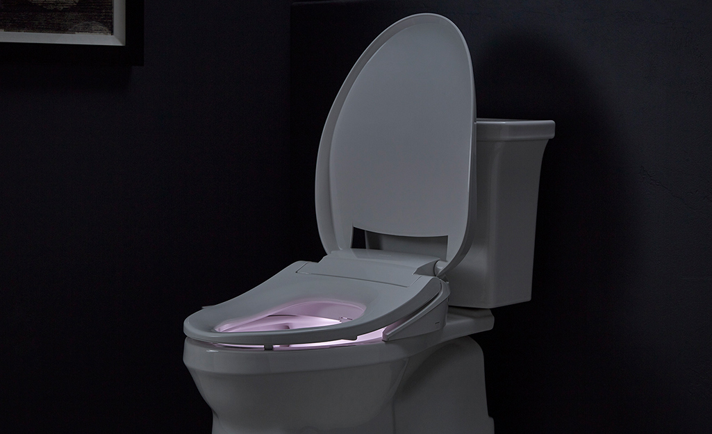 A toilet with a lighted seat in a dark room.
