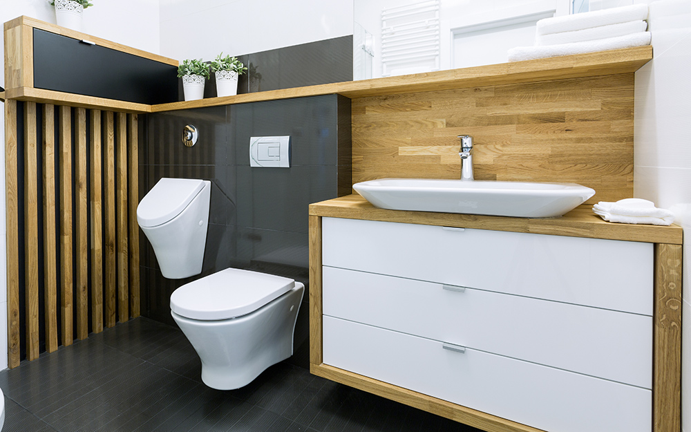 A urinal mounted to a bathroom wall next to a one-piece toilet.