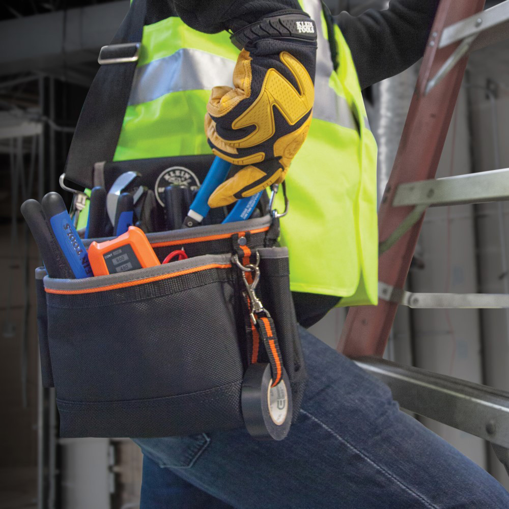 A person is wearing a tool pouch with a strap. 