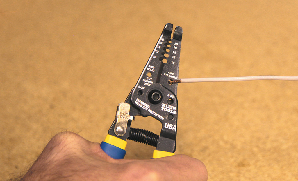 A person uses a pair of wire cutters to cut electrical wire. A person uses a pair of wire cutters to cut electrical wire.