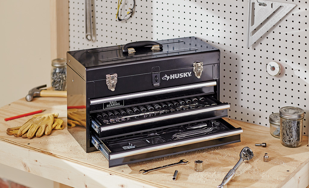 A metal toolbox with drawers open sits on a workbench. A metal toolbox with drawers open sits on a workbench.