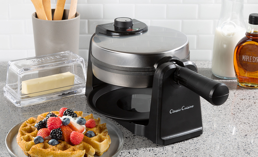 a rotating waffle maker next to a waffle topped with fruit