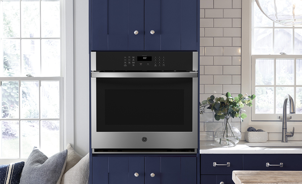 A single wall oven surrounded by blue cabinets.