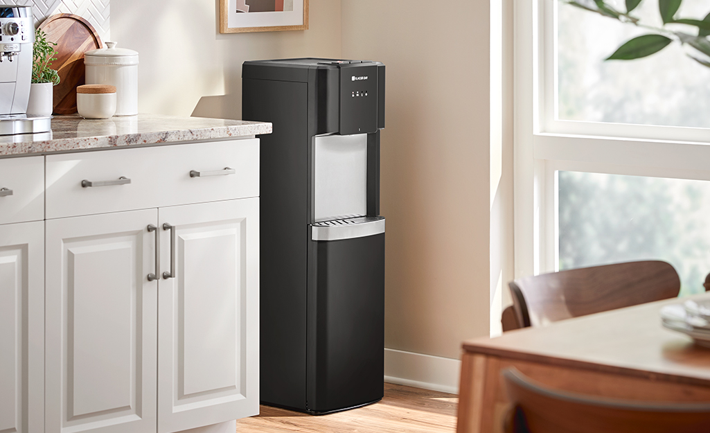 A black cold-water dispenser in the corner of a kitchen.