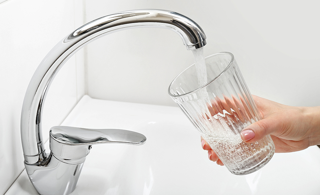 A faucet fills a glass with water.