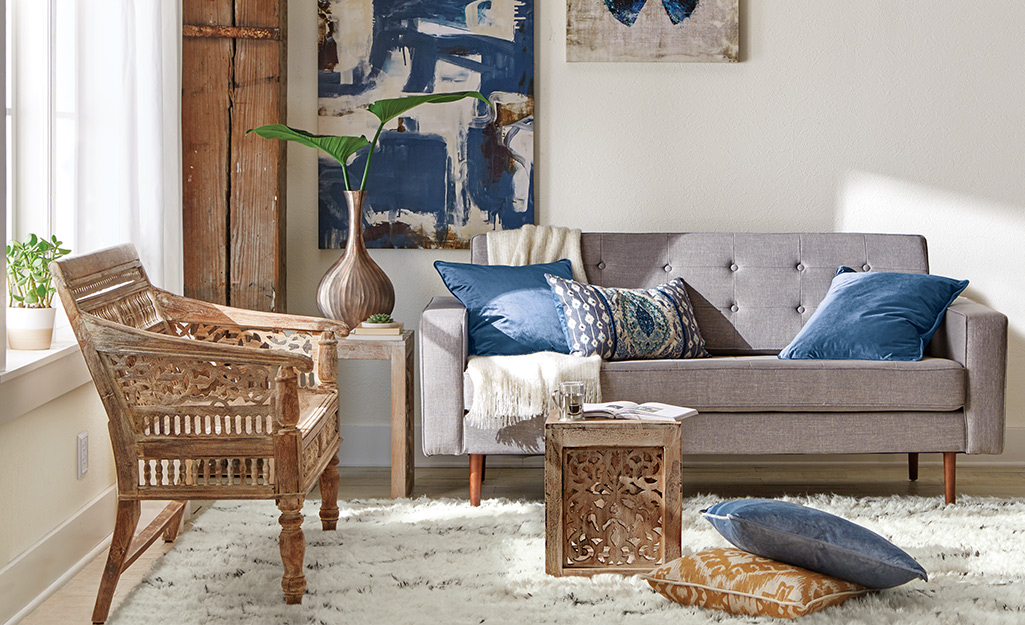 Boho decor in a living room, using a wooden bench, accent rug, couch, throw pillows and wall art.