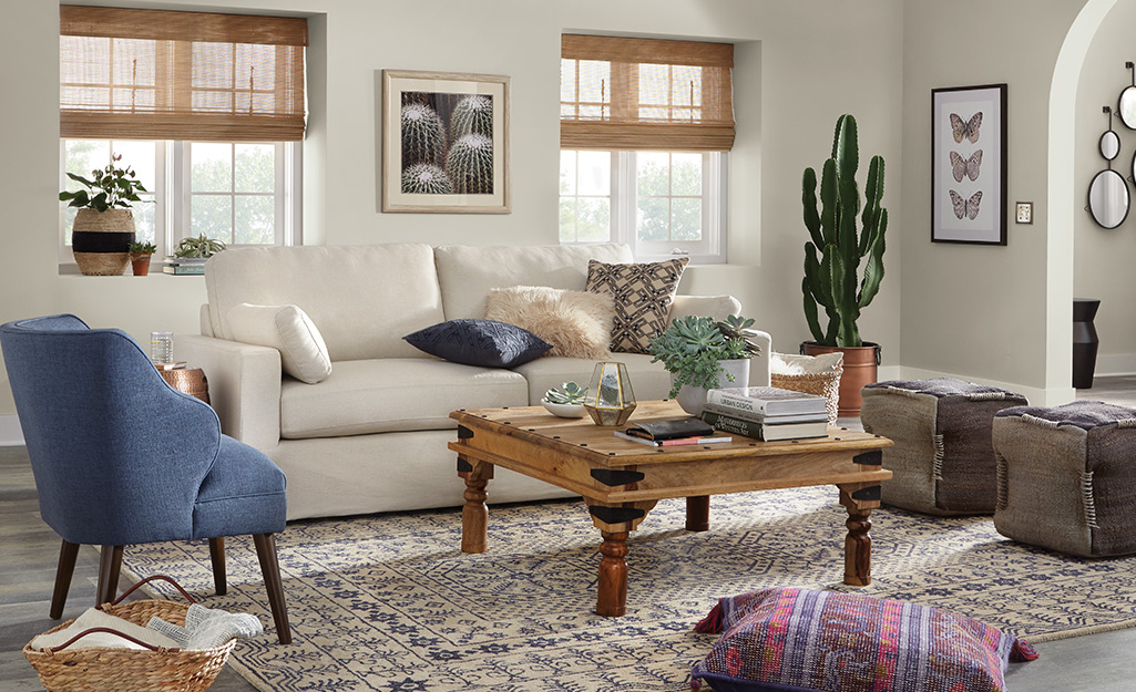A living room decorated minimalist boho style, in neutral colors, with a couch, chair, throw pillows and coffee table.