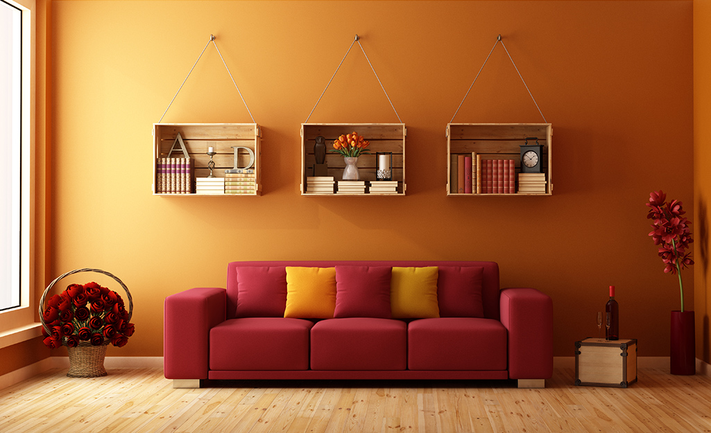 Three wooden crates are used as bookshelves on a living room wall.