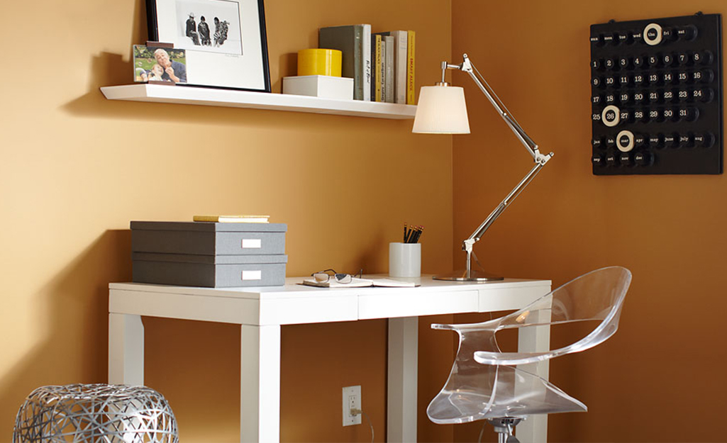 Floating shelves hang on a wall in a home office. 