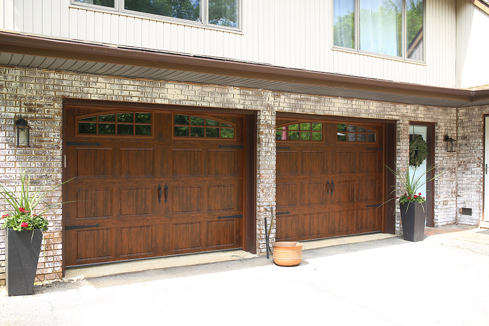 The exterior of a home with two sets of new wooden garage doors.