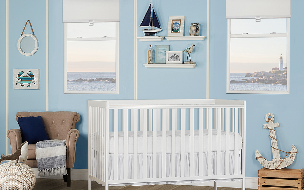 A boy's nursery in traditional blue and white colors with a white crib and blue paint.