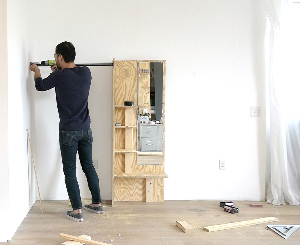 A person connecting the clothing hanging bar to the wall