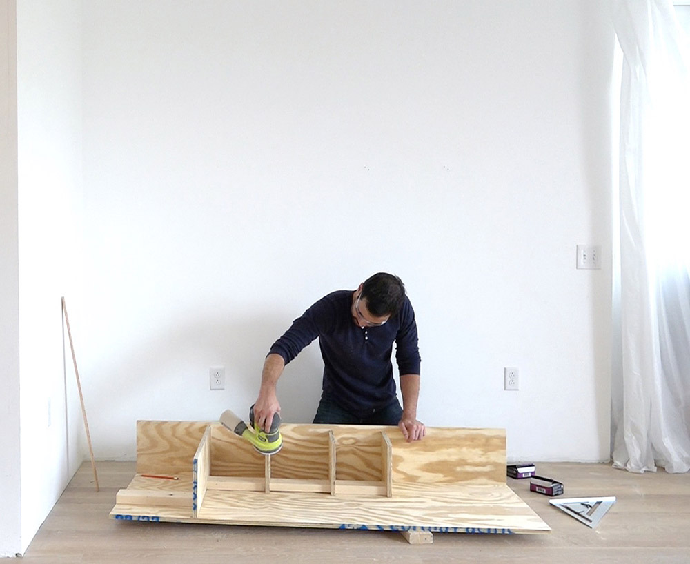 A person sanding down the edges of plywood