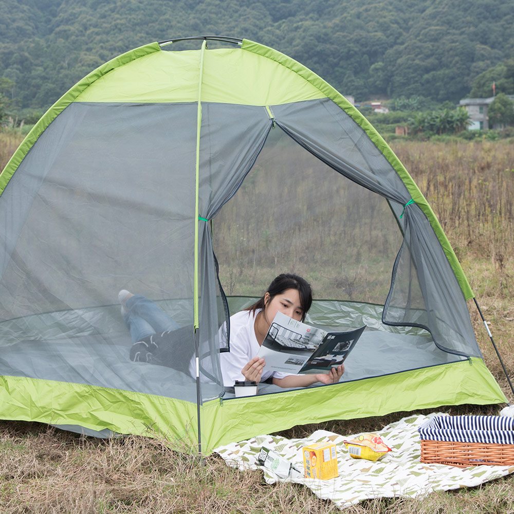 A person reads a magazine while reclining in a tent.