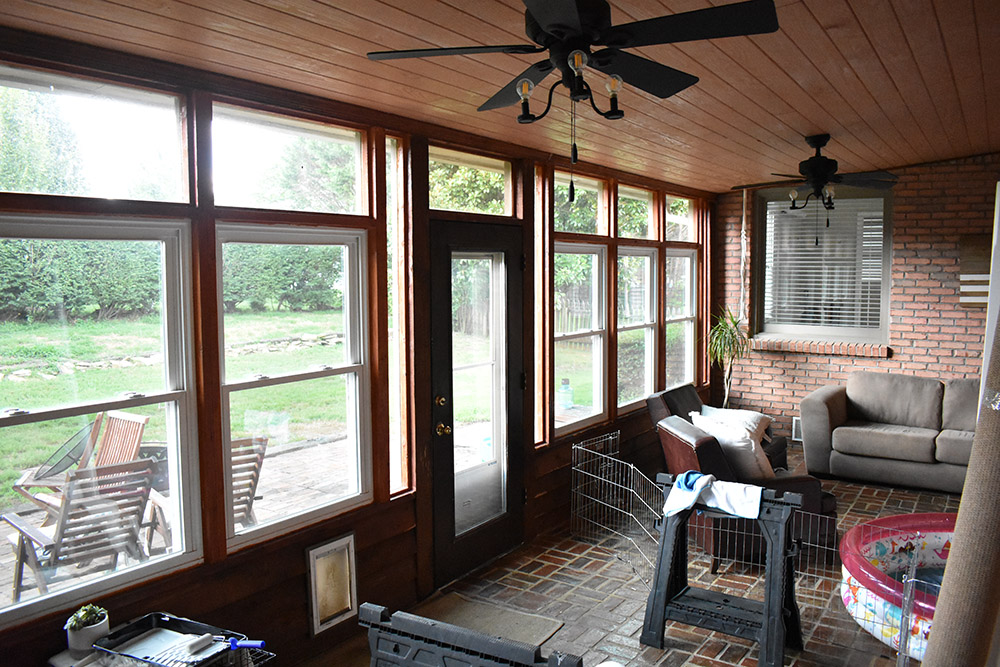 An outdated sunroom with two ceiling fans.
