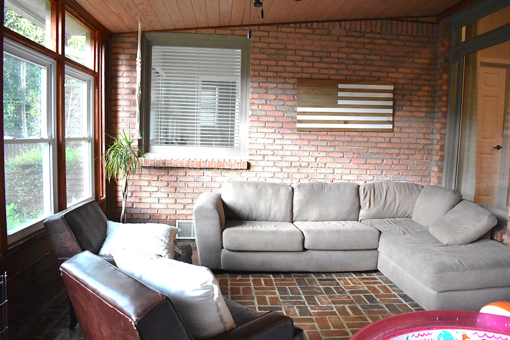 An outdated sunroom with a window on a pink brick wall.