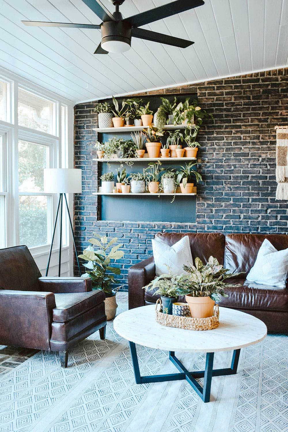 An sunroom with a painted brick wall decorated with shelves of planters.