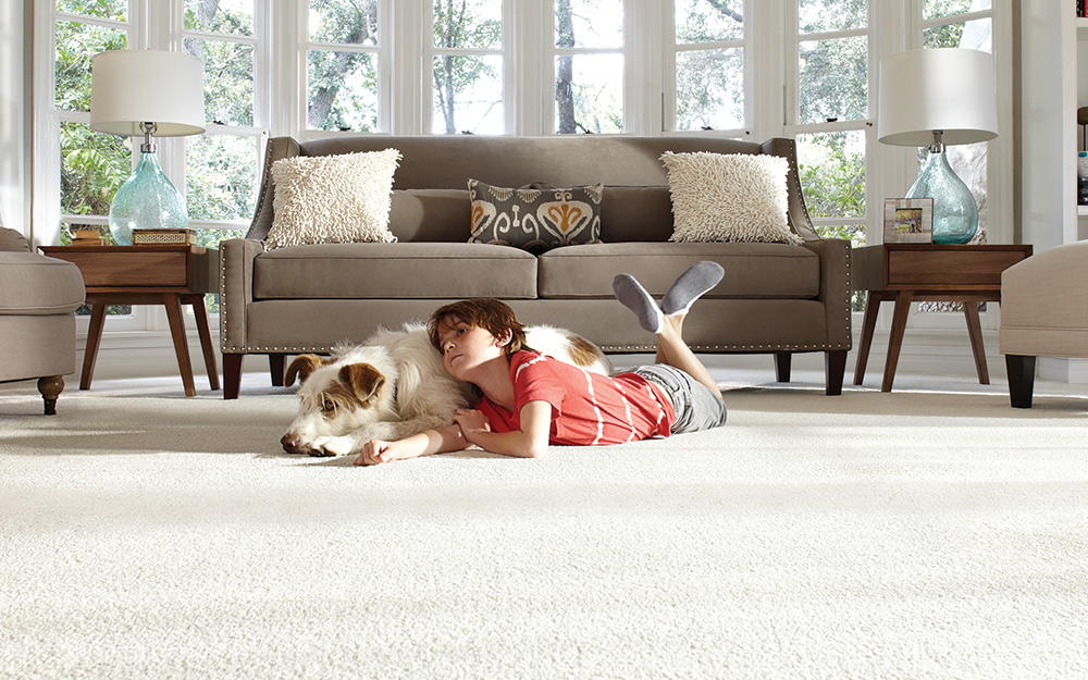 A boy and dog laying on carpet in a living room