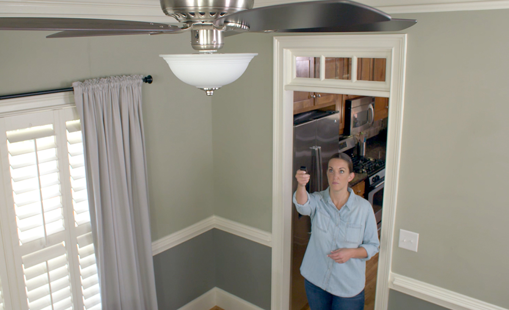 A person using a ceiling fan remote control.