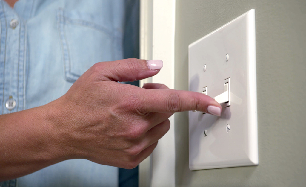 A person checks power to a light switch.