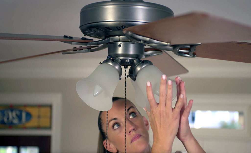 A person works to level a ceiling fan.