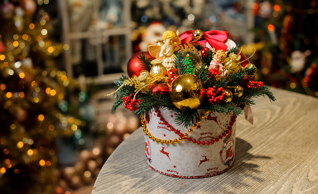 A round Christmas gift box with plants and ornaments in it.