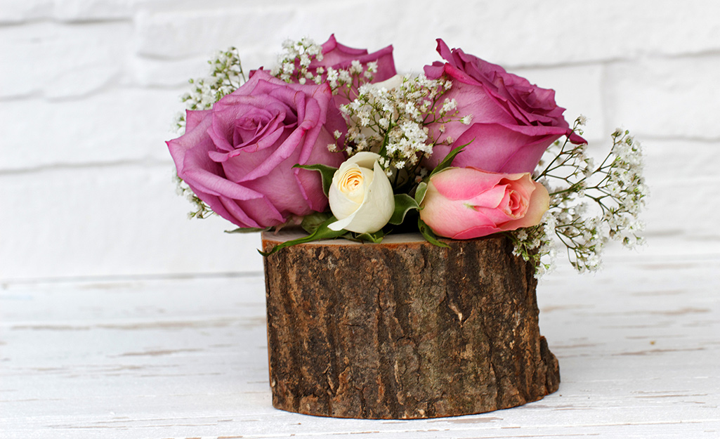 A wood stump with roses in it.