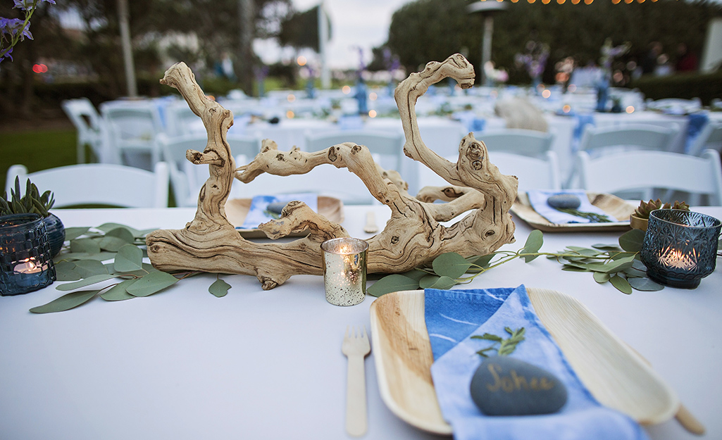 A piece of driftwood on a table with greenery.