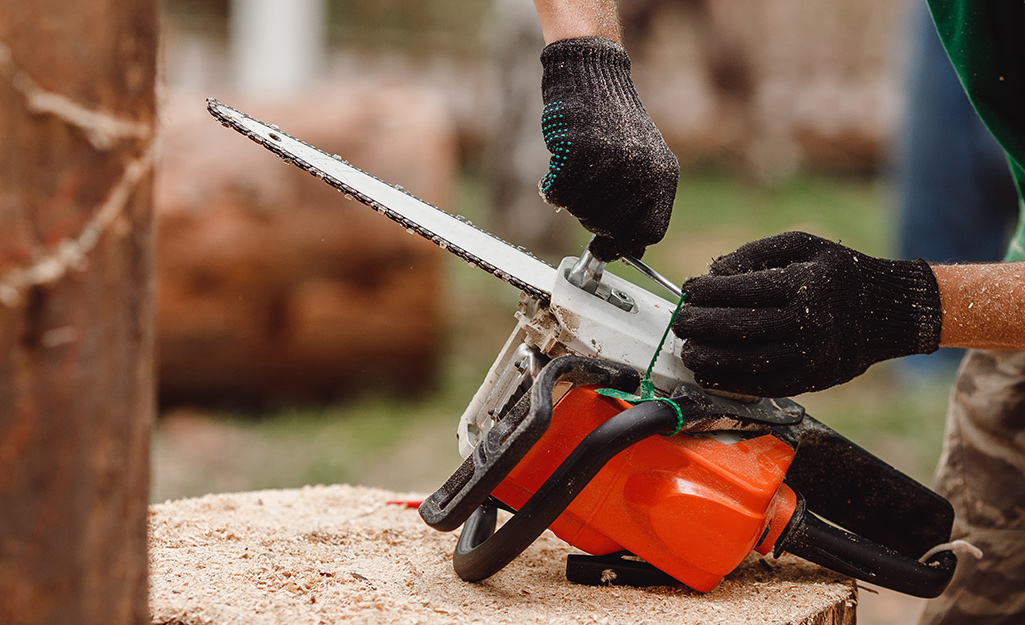 A person wears safety gloves for chainsaw maintenance. A person wears safety gloves for chainsaw maintenance.