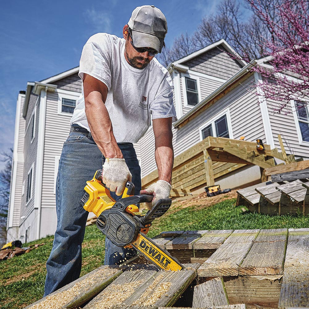 A person using a chainsaw to cut out a wooden deck.