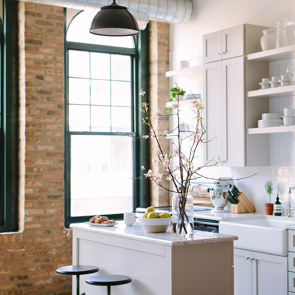 A kitchen space with large windows and a brick accent wall. A kitchen space with large windows and a brick accent wall.