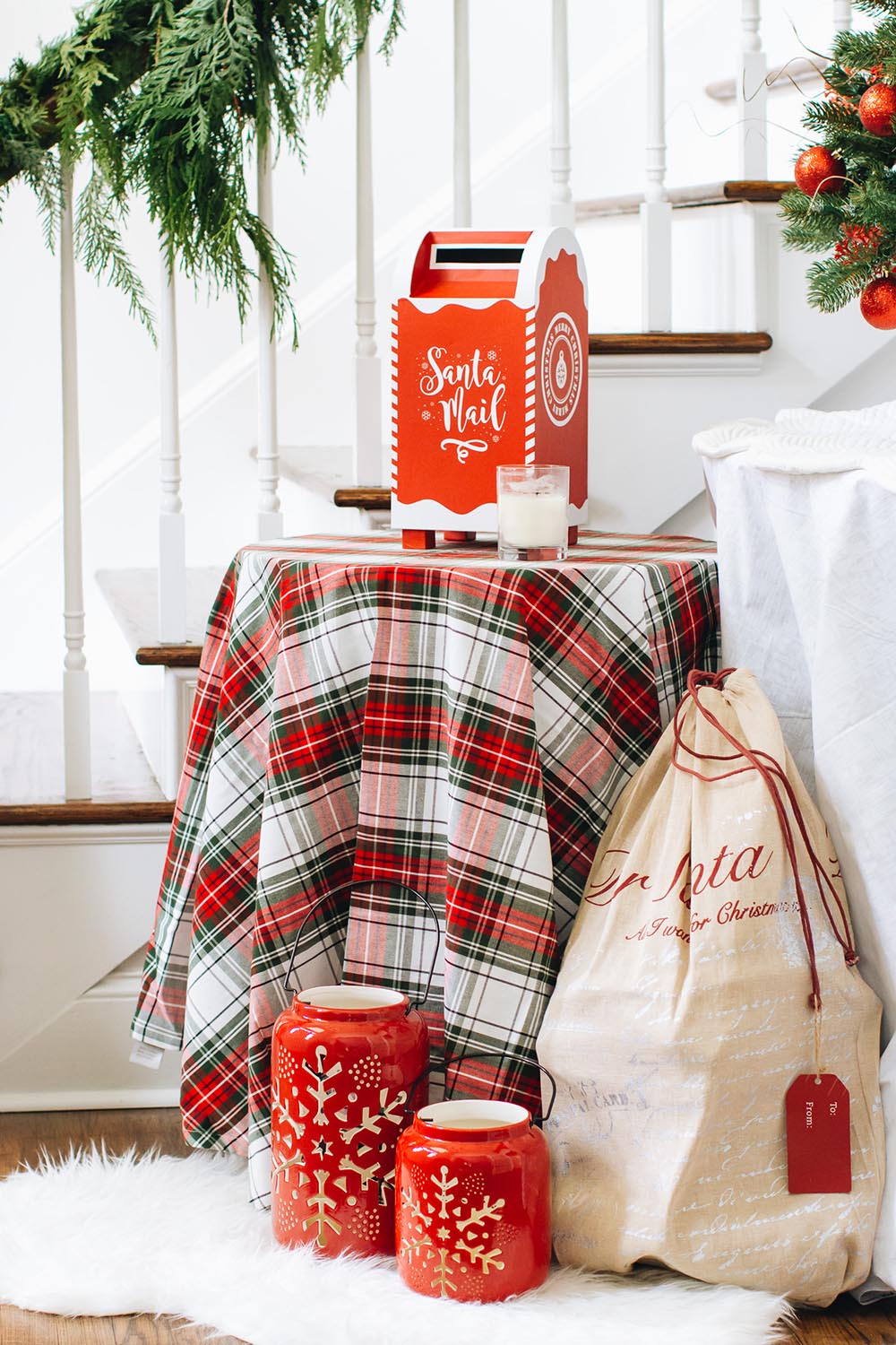 A pair of red lanterns with snowflakes sit in front of table decorated with a plaid tablecloth.