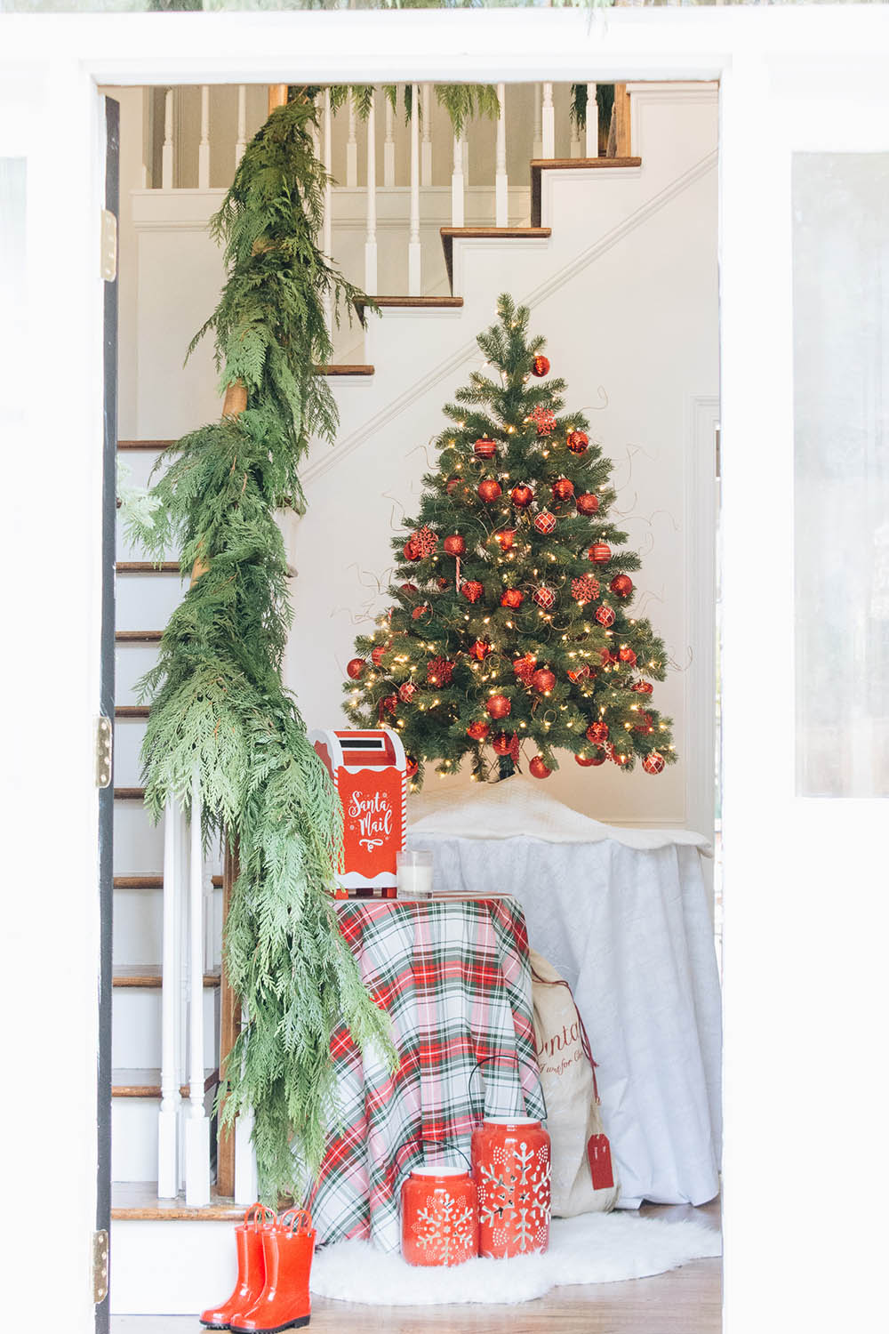 A miniature Christmas tree with red ornaments sitting on an entryway table.