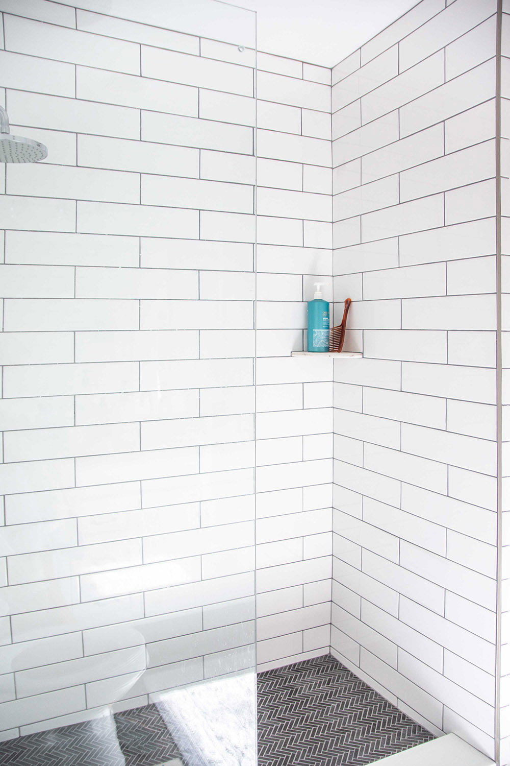 An updated walk-in shower with white tile walls.