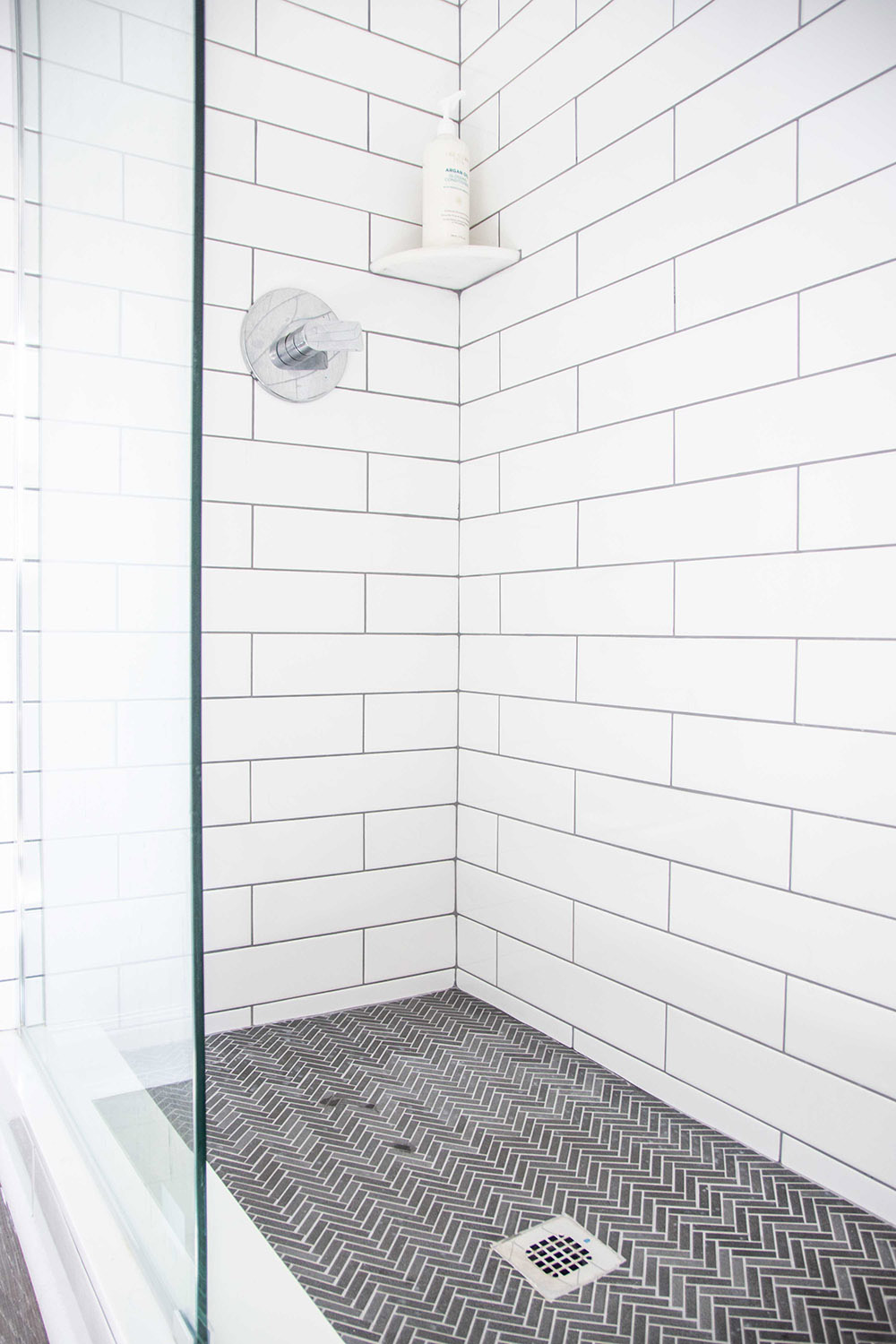 A tiled walk-in shower with a dark mosaic tile floor.