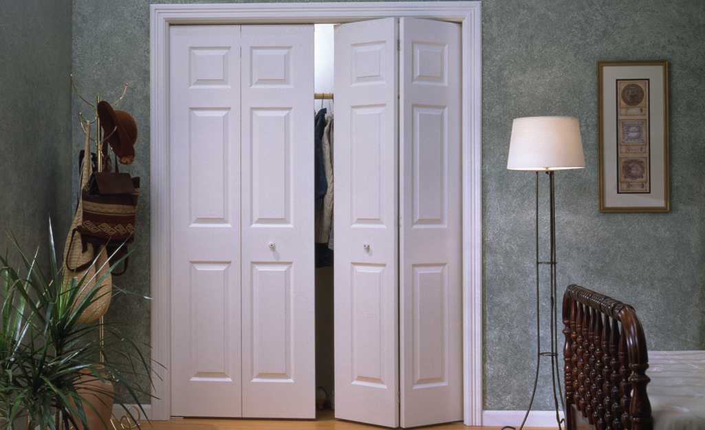 Bifold doors open slightly to show clothes hanging on a rod in a closet.