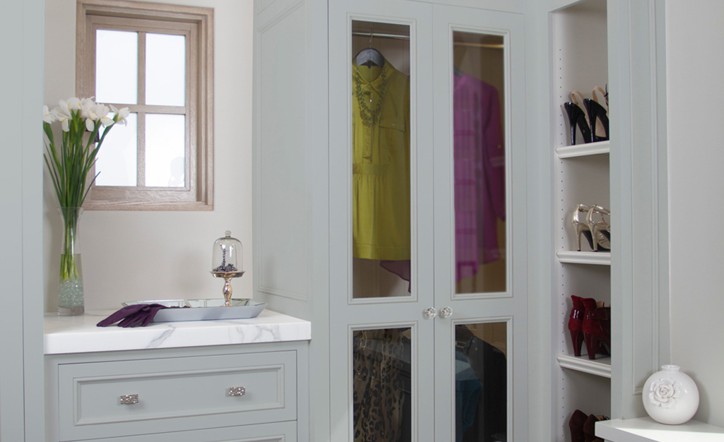 French doors with glass panels show the brightly colored clothes hanging inside a closet.