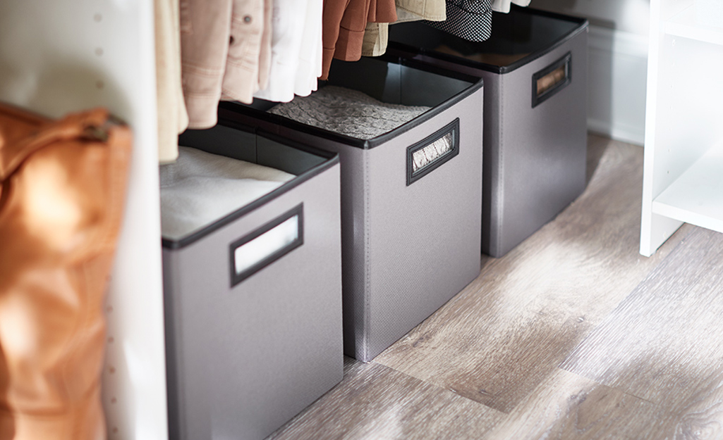 Bins on the floor as a storage option in a closet.