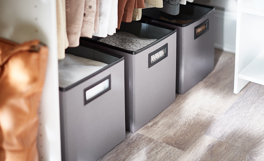 A row of fabric cube storage along the floor of a closet. A row of fabric cube storage along the floor of a closet.