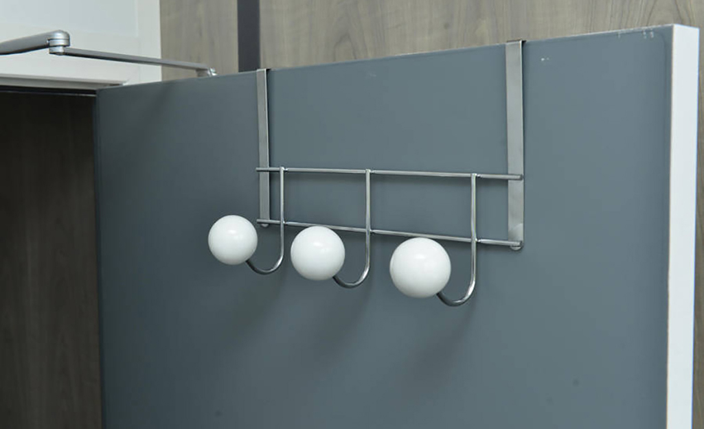 A rack of clothes hooks with large knobs hangs on a door. A rack of clothes hooks with large knobs hangs on a door.