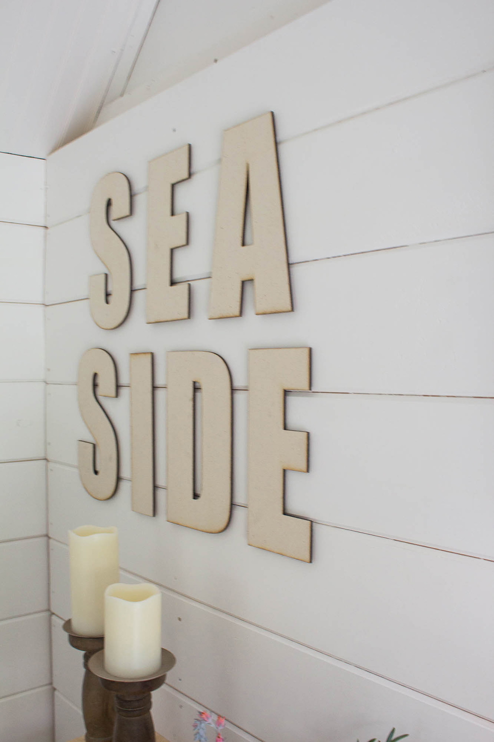 A sign that says 'Seaside' attached to white shiplap walls. A sign that says 'Seaside' attached to white shiplap walls.