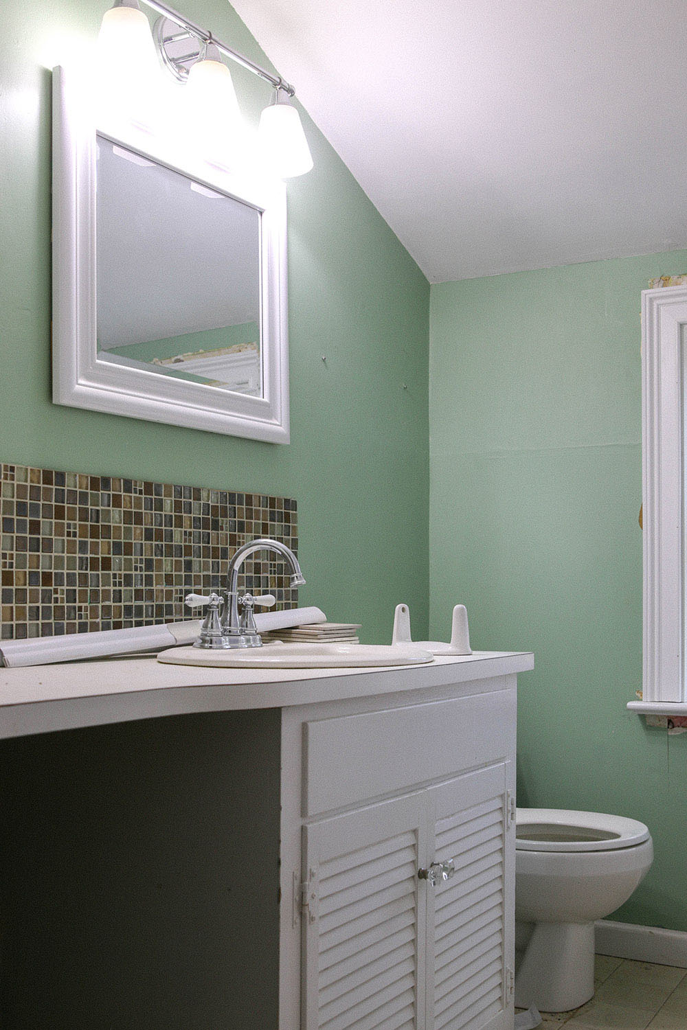 A bathroom with green walls and an old white vanity.